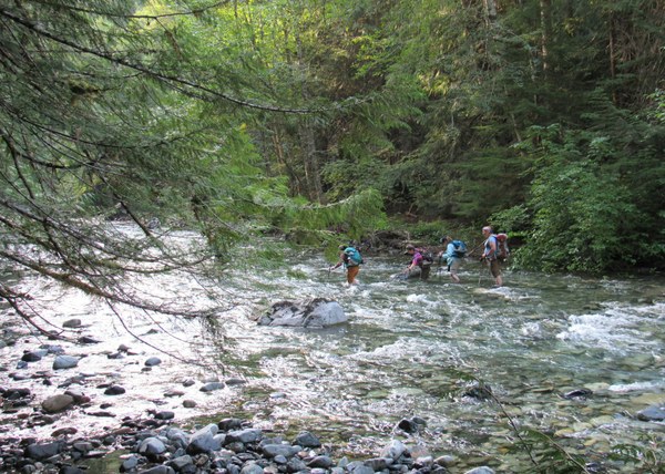 Four hikers crossing a stream