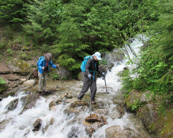 Two hikers crossing a creek