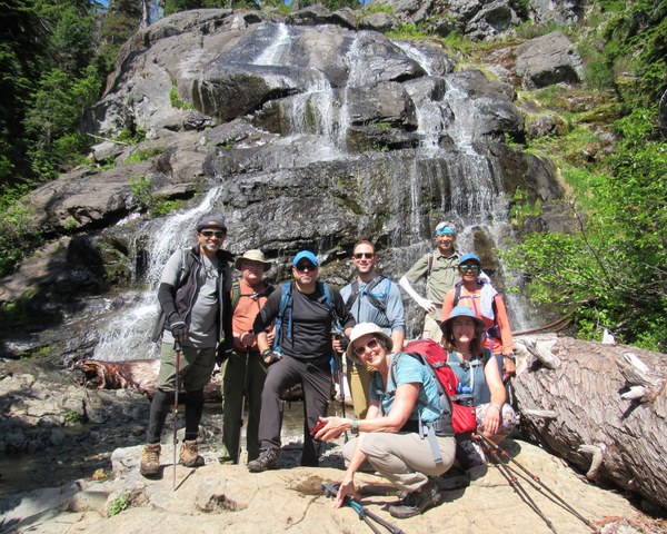 Hikers posing before a large waterfall