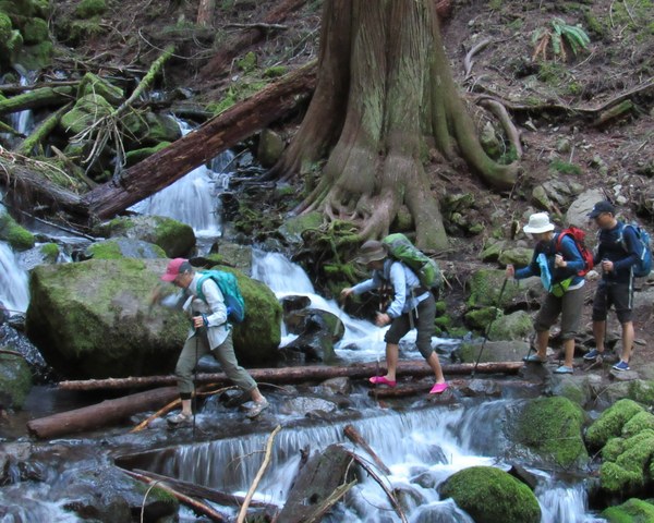 Hikers cross a mountain stream