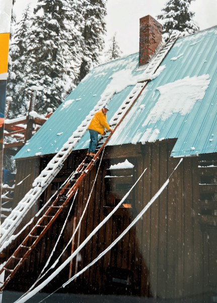 John Hansen climbing a ladder on the roof of the cabin